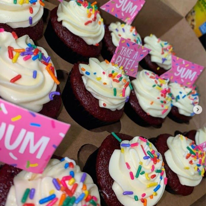 Red velvet cupcakes with white frosting and rainbow sprinkles